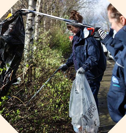 Two volunteer litter pickers picking up rubbish along the roadside.